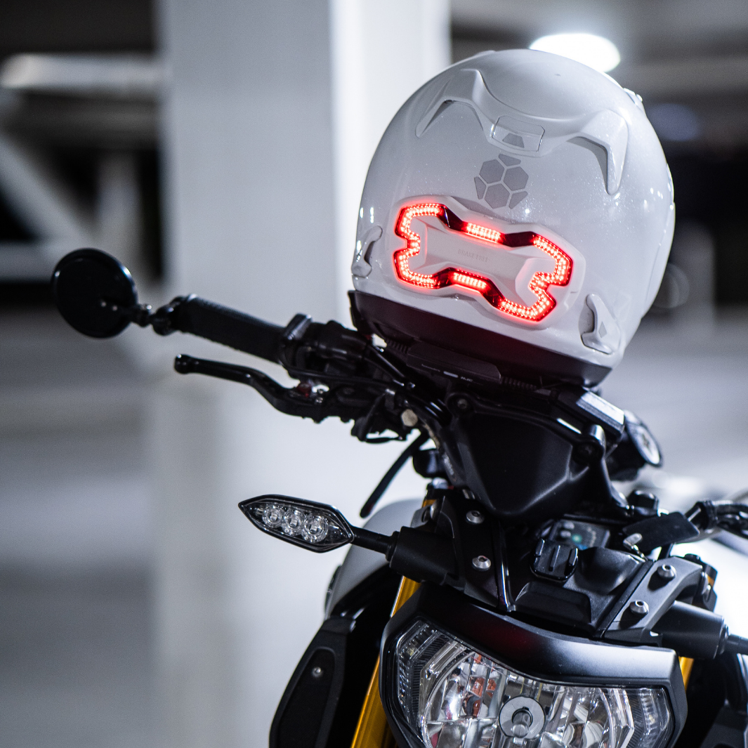 White Brake Free mounted on a white Arai helmet shown on the handle bars of a motorcycle